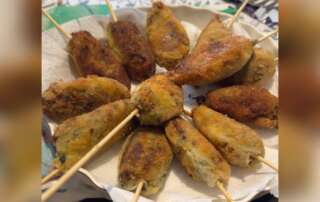 stecchi genovesi fritti su stecco, ricetta stecchi zeneixi con borragini, stecchi ripieni liguri panati, preparazione stecchi tradizionali genovesi, close up stecchi dorati con ostia
