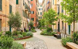 Scena urbana realistica a Genova con area depavimentata, meno asfalto e nuove superfici permeabili con verde e piccoli alberi